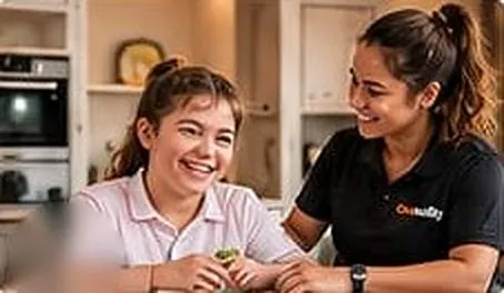 Support worker sharing a laugh with a young woman at a kitchen table